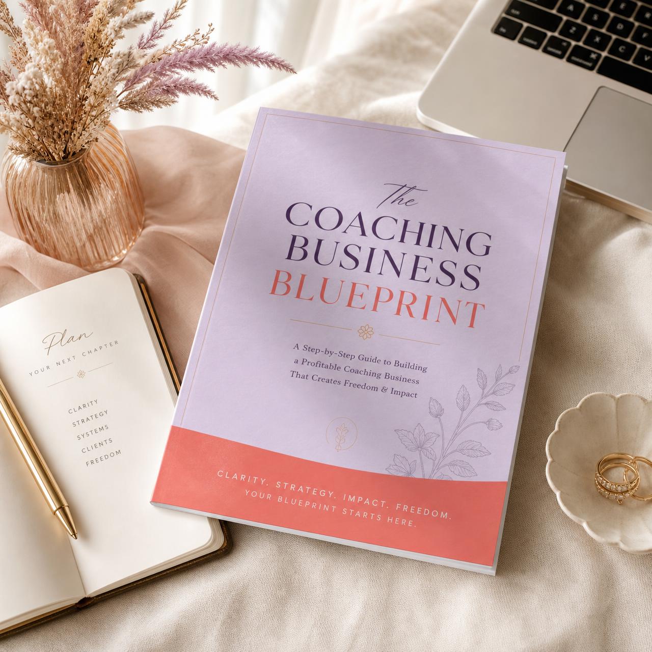 The Coaching Business Blueprint guide styled on a linen desk with a notebook and laptop